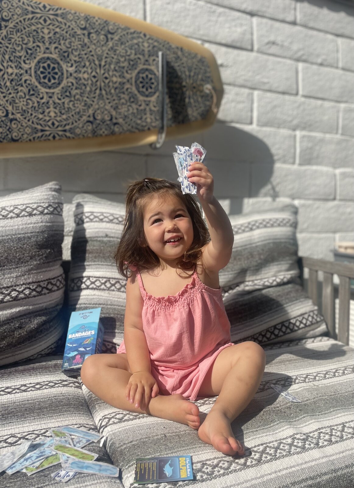 A smiling child holding up a WaveAid ocean-animal bandage.