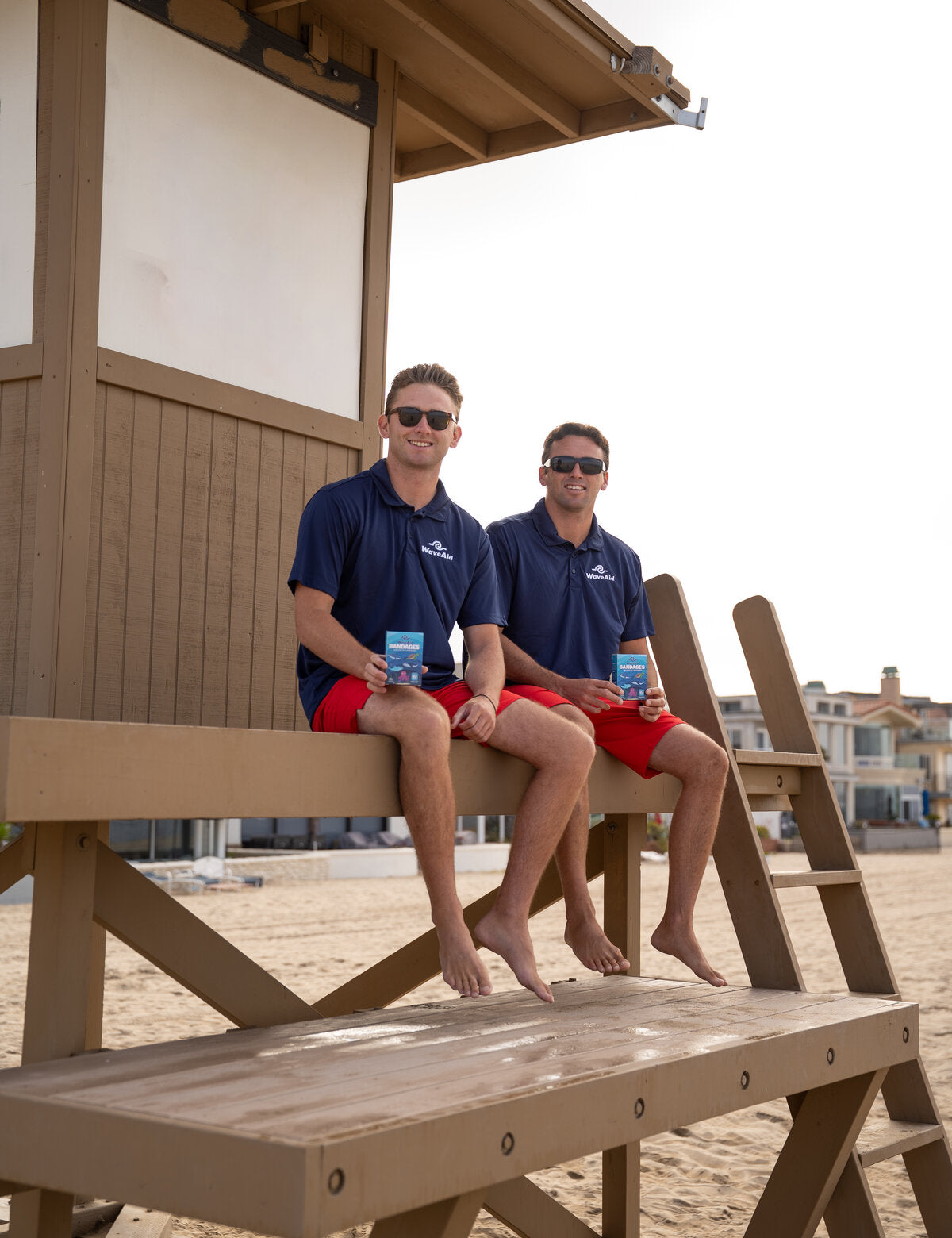 Foster and Michael, WaveAid co-founders, on the Newport Beach lifeguard tower with WaveAid boxes in hand.